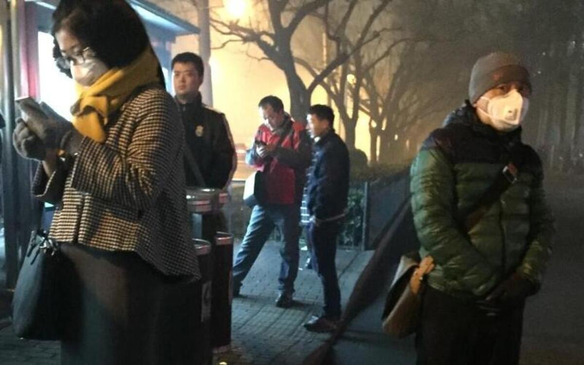Beijing commuters wait for buses amid some of the city’s worst smog this year on Monday, Nov. 30, 2015. Although most Beijing residents do not wear masks on a regular basis, more and more are wearing them on the city’s worst days for air pollution.