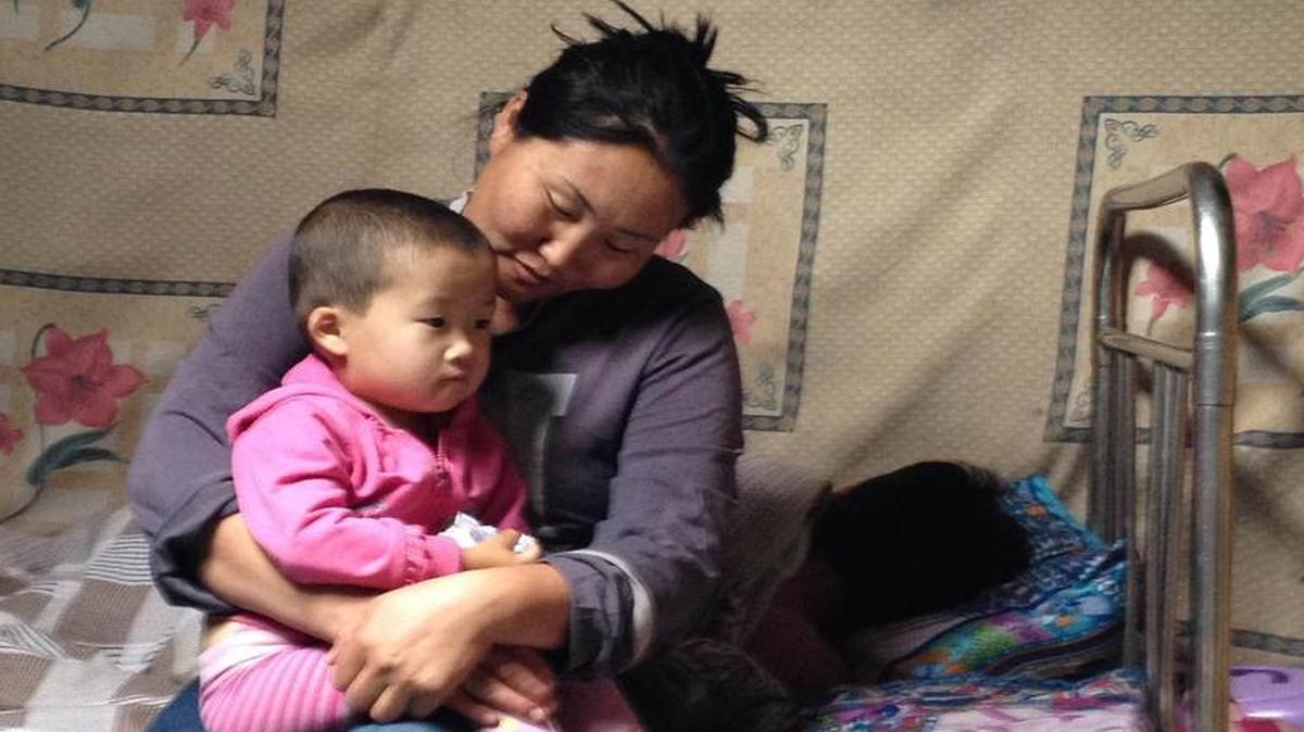 
Unurbileg, a Mongolian herder, holds one of her daughters, Bujinlkham, age 2, inside the family's yurt in grasslands near the Tuul River in central Mongolia, July 13, 2015. Her husband, Duuree, sleeps in the background after a long day of watching and herding the family's sheep, horses and other animals. Unurbileg -- who like many Mongolians only uses one name -- says her family is doing well, evidenced by the satellite dish and new Toyota SUV they have outside their yurt. But she worries about the future. A single cold winter could wipe out the family's wealth, their livestock.
