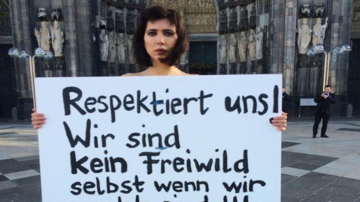 A Swiss performance artist disrobed outside Cologne’s cathedral on Friday to protest alleged sexual assaults perpetrated on New Year’s Eve. Her sign reads “Respect us! We are not fair game even when we are naked!!!” Police announced that they’d arrested two young asylum seekers in what is now 200 reported assaults during New Year’s Eve mayhem near the cathedral.