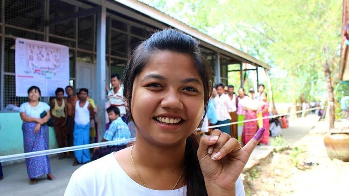 May Thinzar Cho, 22, shows off her ink-stained finger after voting for the first time Sunday in Pandaing, a village in the Irrawaddy Delta region of Myanmar. The ink is intended to prevent repeat voting.