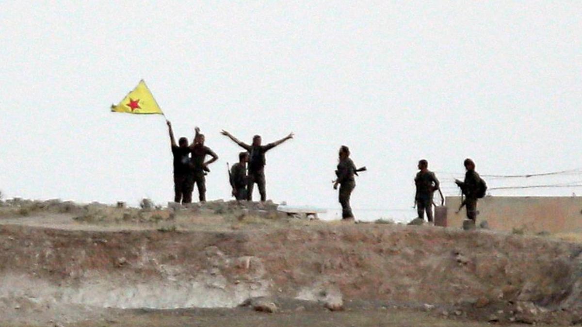 
Fighters with the Kurdish People's Protection Units, or YPG, waved their yellow triangular flag on the outskirts of Tal Abyad, Syria, after seizing the town June 15 from the Islamic State. Tuesday, Islamic State fighters counter attacked.
