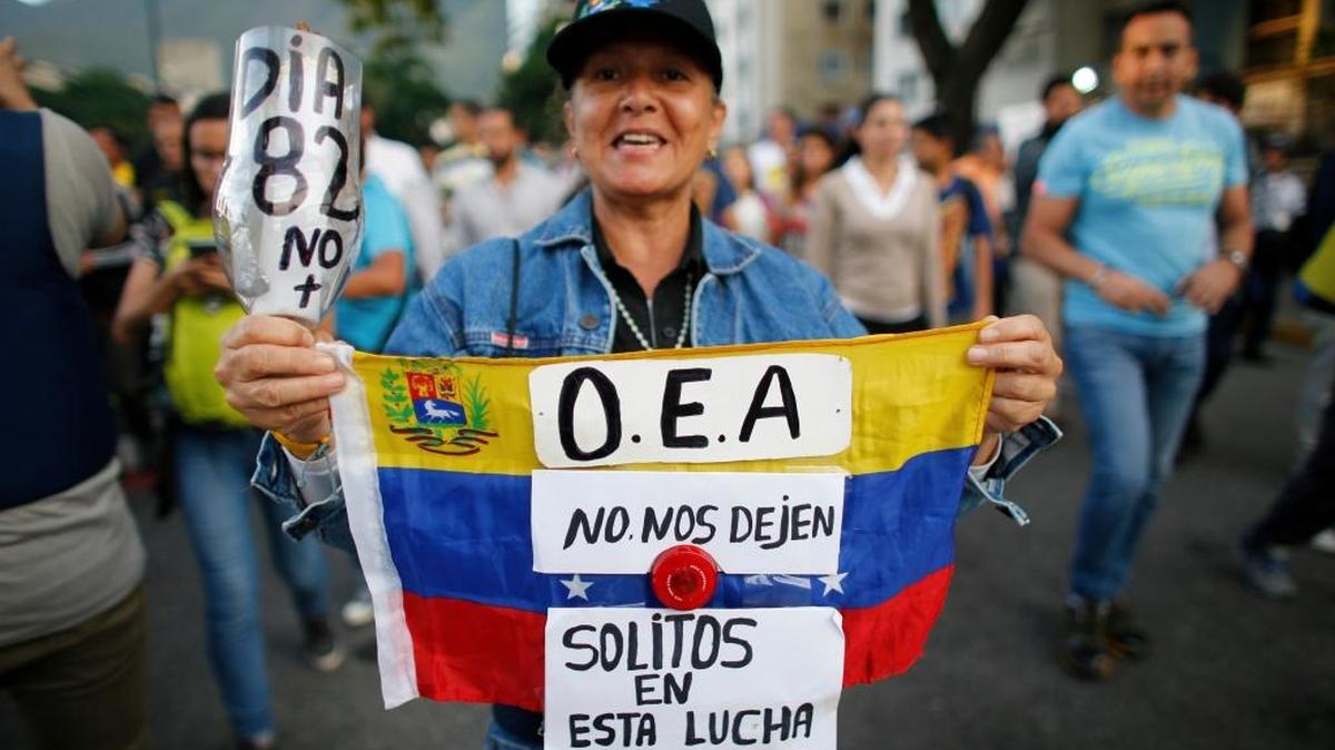 A demonstrator holds up a Venezuelan national flag with a message that reads in Spanish; "OAS, don't leave us alone in this fight", in Caracas, Venezuela, Wednesday, June 21, 2017.