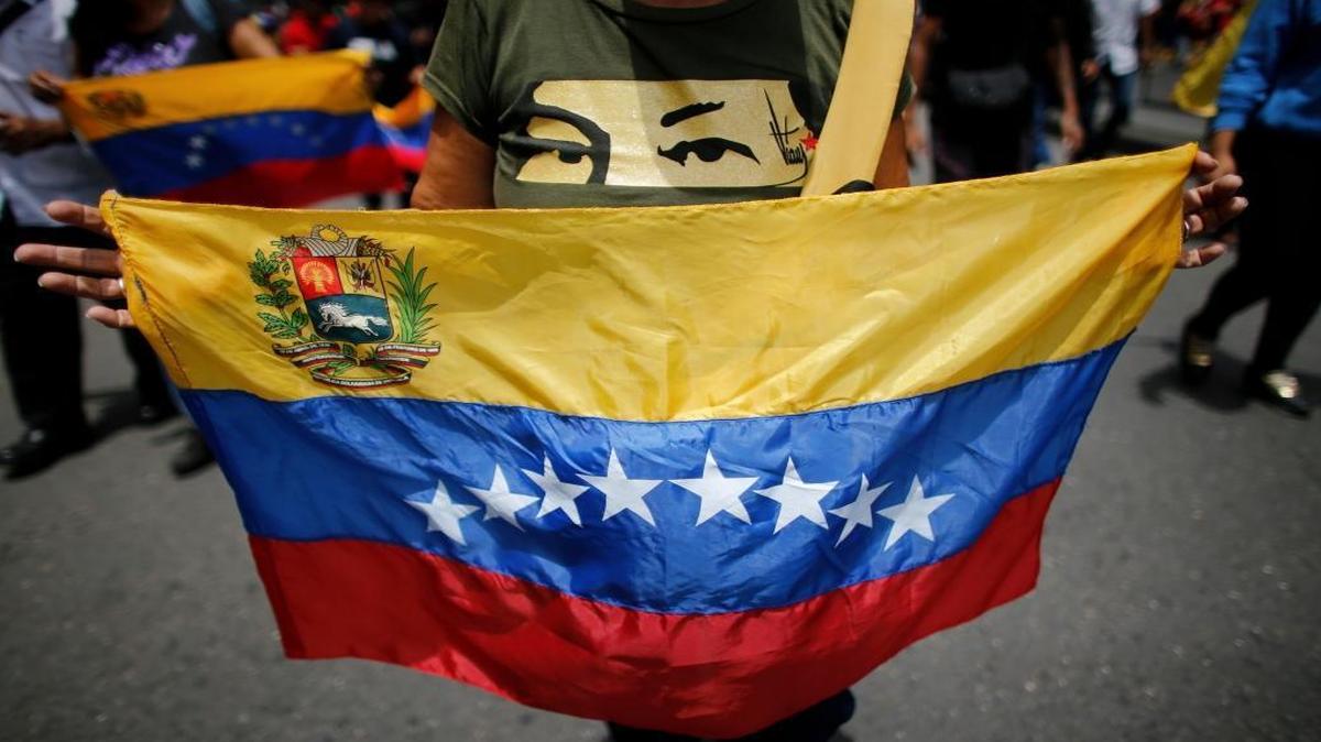 A government supporter wears a T-shirt featuring a stencil of late President Hugo Chavez's eyes and holds a national flag, during an anti-imperialist march to denounce Trump's talk of a "military option" for resolving the country's political crisis in Caracas, Venezuela, Monday, Aug. 14, 2017.