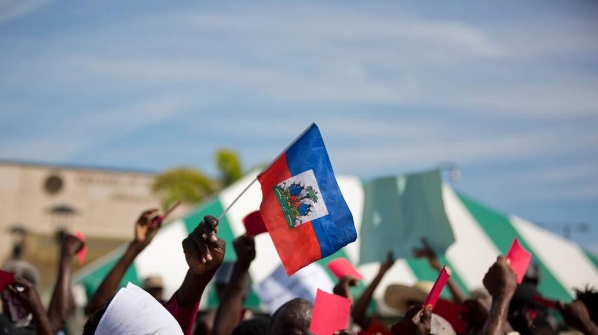 A Haitian holds a national flag outside the U.S. embassy where dozens gathered to protest against President Donald Trump's recent disparaging comments about Haiti and African nations, in Tabarre, a district of Port-au-Prince, Haiti, Thursday, Jan. 18, 2018.