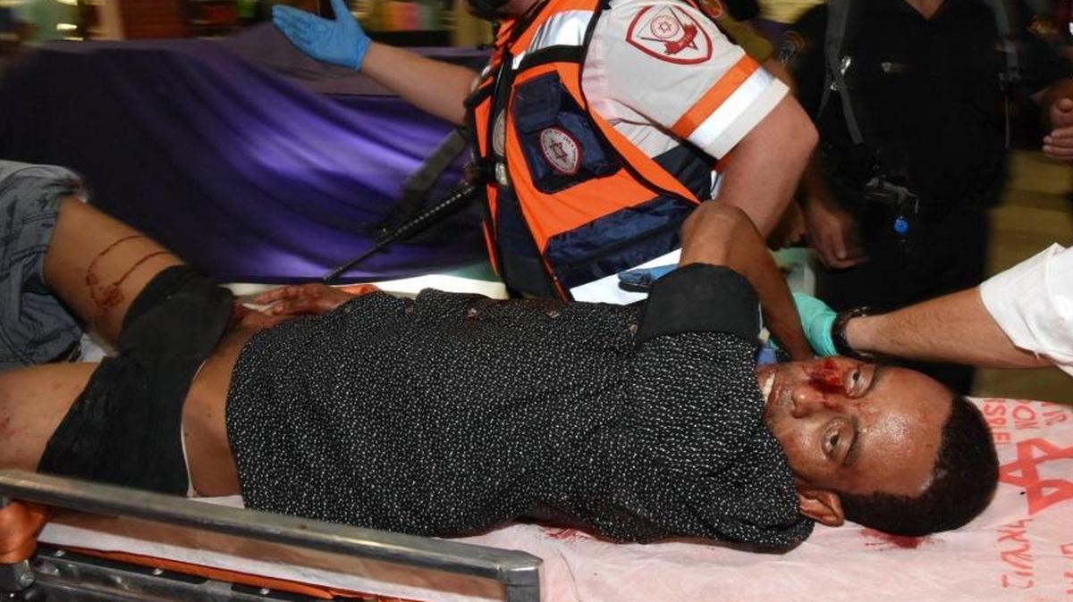 A beaten Habtom Zerhom is carried from the bus station in Beersheba, Israel, on Sunday. Security camera footage showed him being shot by an Israeli security guard as he crawled on the ground, then kicked by bystanders as he lay in a pool of blood.