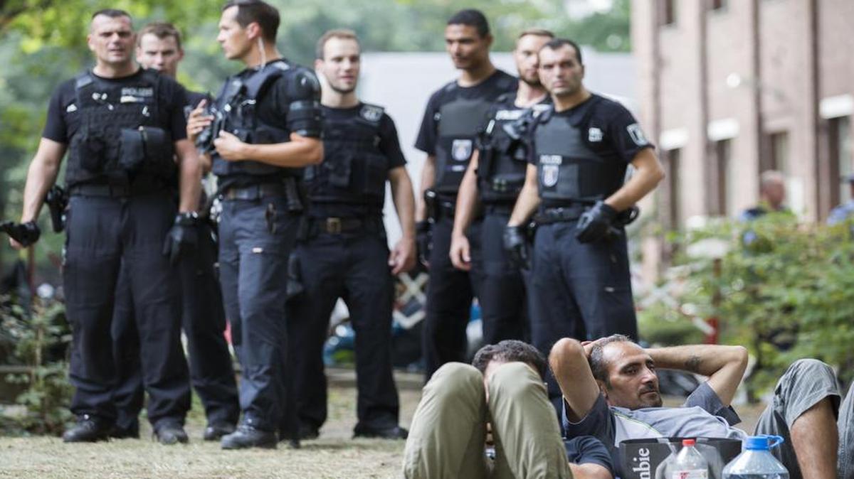
Police keep watch on asylum seekers lying on the grass in front of the reception center for refugees in Berlin on Aug. 7, 2015. 
