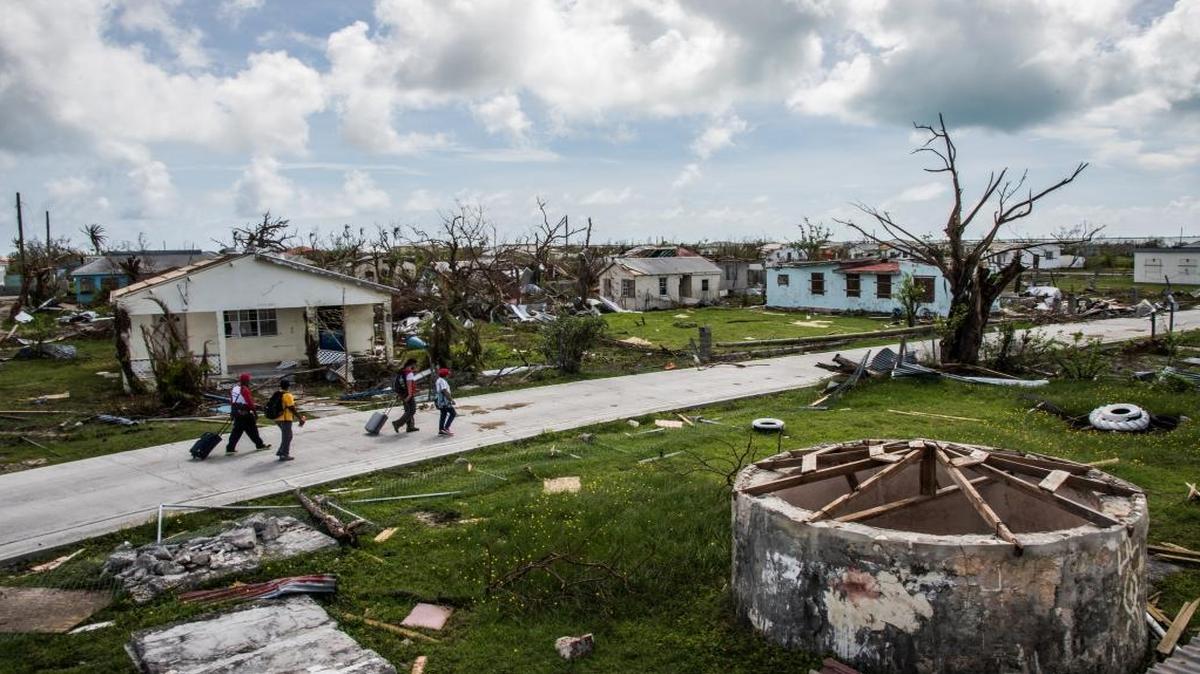 A Red Cross crew accompanies Peter Cuffy and his wife, Jenita Cuffy, as they walk through Codrington, their town on the island of Barbuda, in the aftermath of Hurricane Irma. Their home is among the many damaged by the storm.