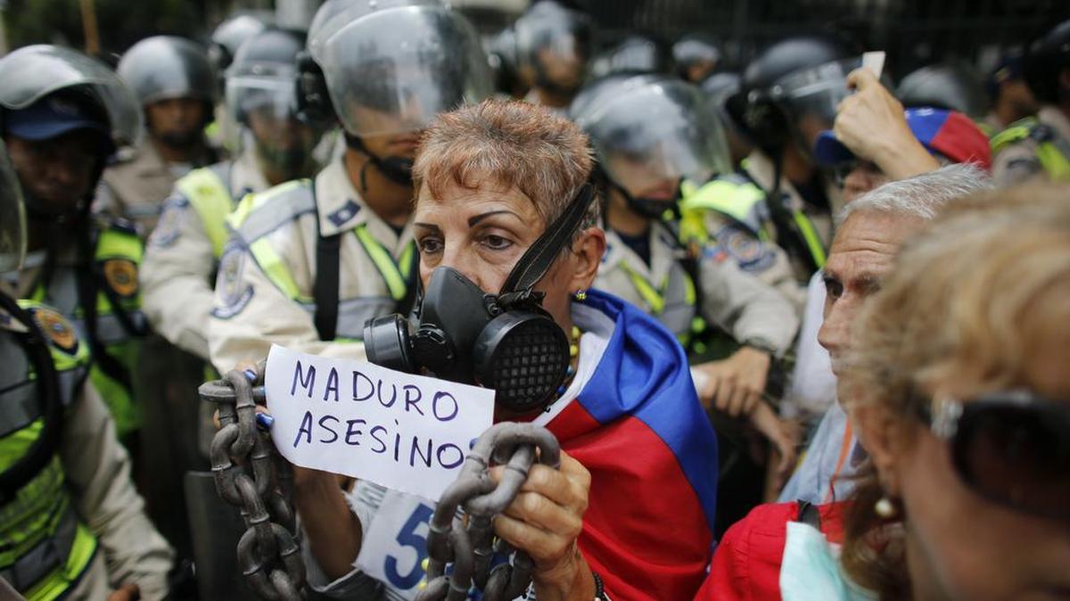A woman holds a handwritten message that reads in Spanish: "Maduro Murderer" during a protest of elderly Venezuelans against President Nicolas Maduro in Caracas, Venezuela, Friday, May 12, 2017. The protest billed as the "March of the Grandparents" comes on the heels of six weeks of political unrest that have left some three dozens killed.