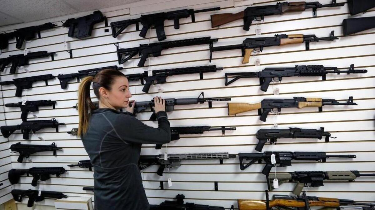 Gun shop owner Tiffany Teasdale-Causer returns a Ruger AR-15 semi-automatic rifle to its place on a wall with dozens of other semi-automatic rifles, Tuesday, Nov. 7, 2017, in Lynnwood, Wash.