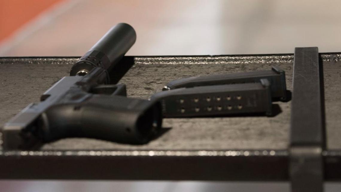 A handgun with a silencer and two magazines are shown at a gun range in Atlanta. For decades, buying a silencer for a firearm has been as difficult as buying a machine gun, requiring a background check that can take close to a year.