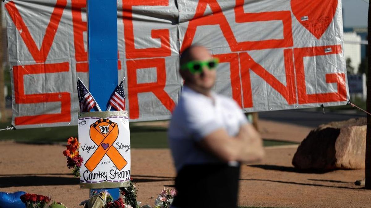 Gareth Wilkinson stands near a makeshift memorial in honor of the victims of a mass shooting.