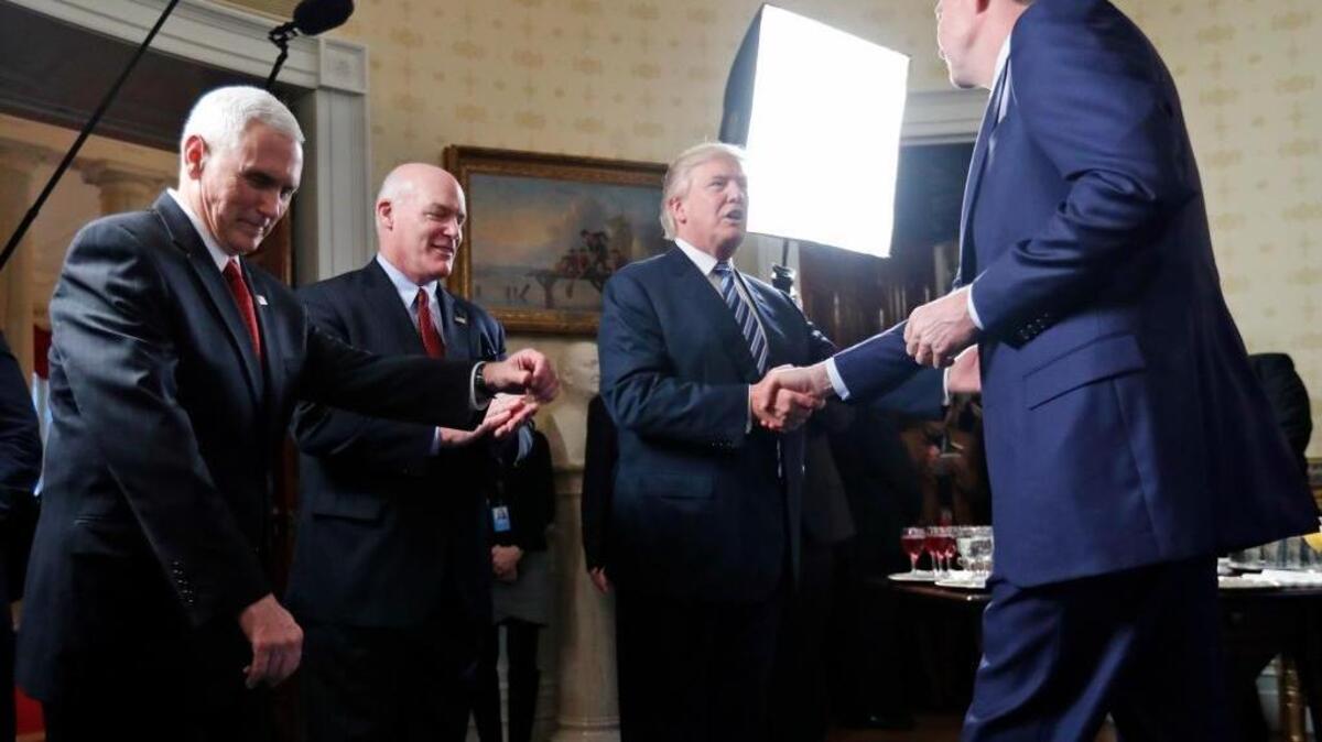 Vice President Mike Pence, left, and Secret Service Director Joseph Clancy stand as President Donald Trump shakes hands with FBI Director James Comey during a reception for inaugural law enforcement officers and first responders in the Blue Room of the White House, Sunday, Jan. 22, 2017 in Washington.