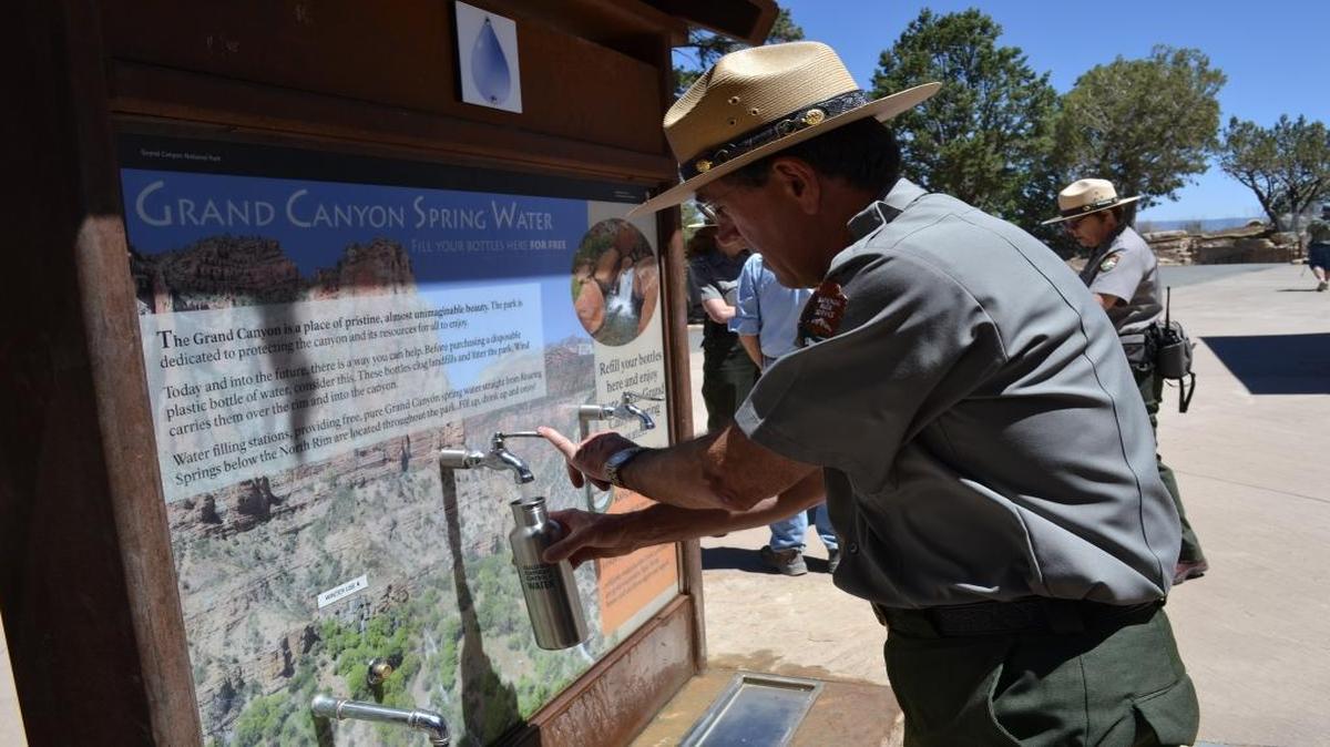 A park official at Grand Canyon National Park fills a reusable bottle with water from a hydration station. Grand Canyon is one of 20 national park units that have banned sales of bottled water to reduce litter. The bottled-water industry is lobbying Congress to overturn that ban.