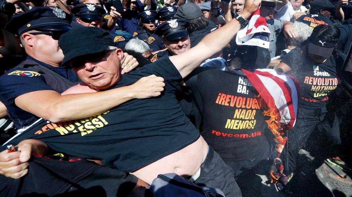 In this July 20, 2016, file photo, a law enforcement officer takes Gregory "Joey" Johnson into custody after he started to burn an American flag in Cleveland, during the third day of the Republican convention. President-elect Donald Trump said Tuesday that anyone who burns an American flag should face unspecified "consequences," such as jail or a loss of citizenship _ a move that was ruled out by the Supreme Court nearly three decades ago.