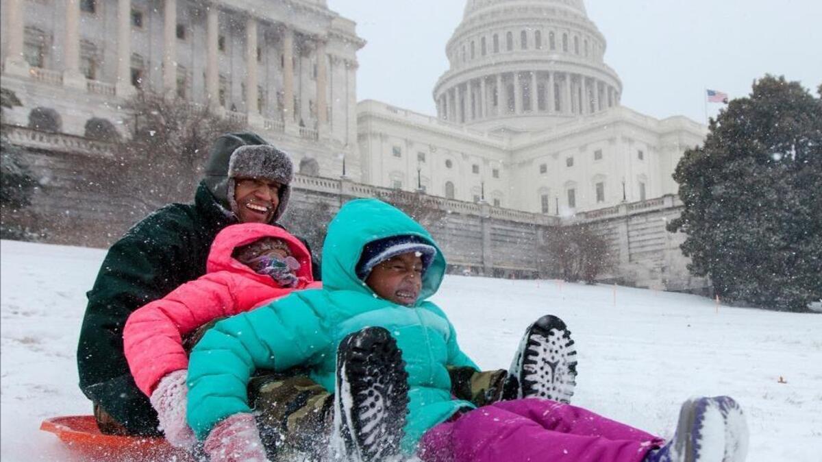 Bashon Mann and his children sled down a hill at the Capitol as snow falls in Washington, Tuesday, Jan. 21, 2014. A provision in a spending bill that Congress will vote on this week would lift a ban on sledding on the Capitol grounds.
