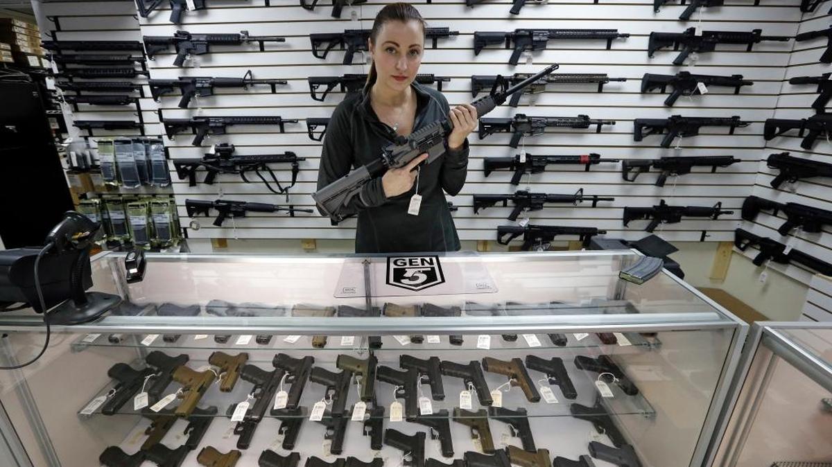 Gun shop owner Tiffany Teasdale-Causer poses for a photo with a Ruger AR-15 semi-automatic rifle, the same model, though in gray rather than black, used by the shooter in a Texas church massacre two days earlier.