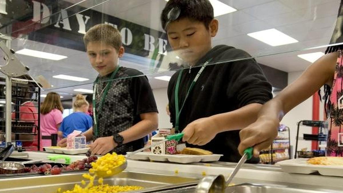 
The lunch program at Plaza Middle School in Kansas City, Mo., features a variety of healthy offerings. On Sept. 10, 2015, students Garrett Winheim, Evan Nguyen and Laniya Harris, left to right, select from items on the vegetable bar that include local organic zucchini, corn, grapes and a mixed salad.
