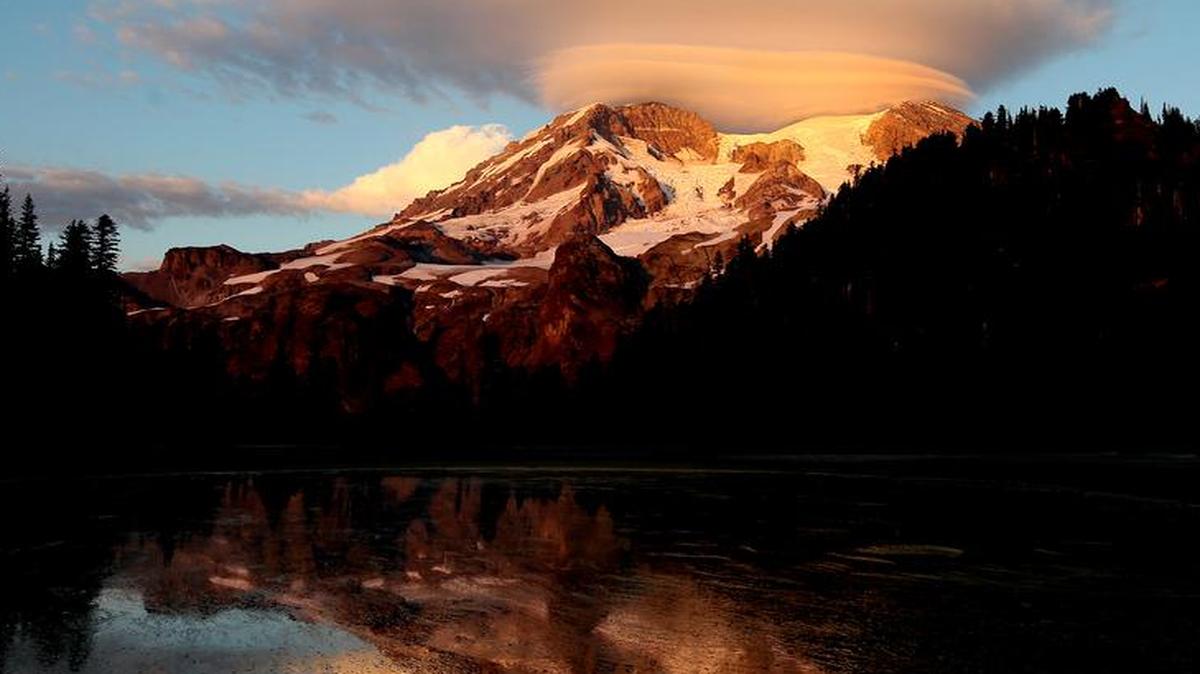 In this September 2012 photo, a cloud hovers over Mount Rainier at sunset in a view from Klapatche Park Camp at Mount Rainier National Park in Washington.