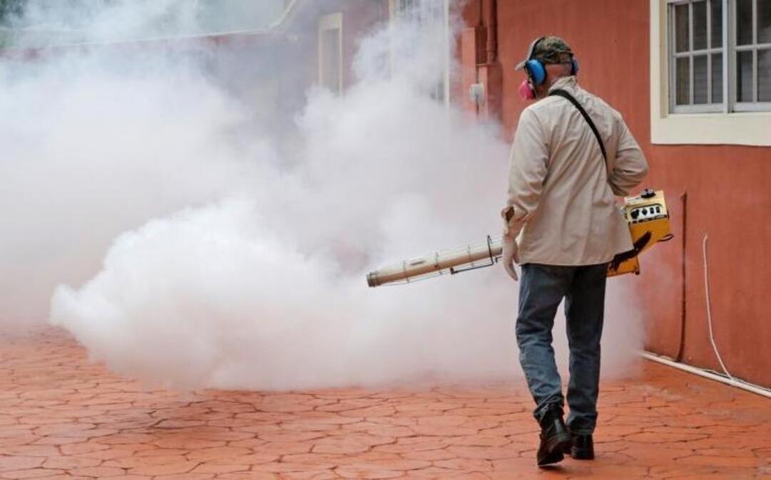 A Miami-Dade County mosquito control worker sprays around a home in the Wynwood area of Miami on Aug. 1, 2016.