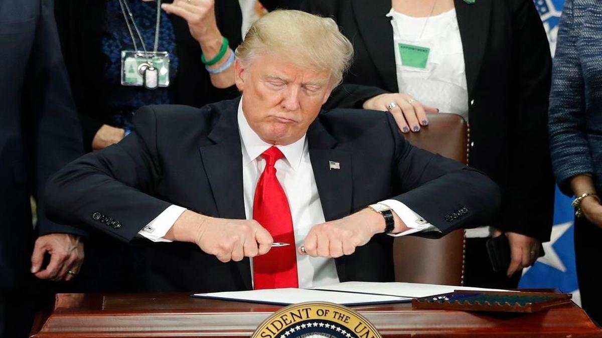 In this Jan. 25, 2017, file photo, President Donald Trump uncaps a pen to sign an executive order for immigration actions to build a border wall during a visit to the Homeland Security Department in Washington.