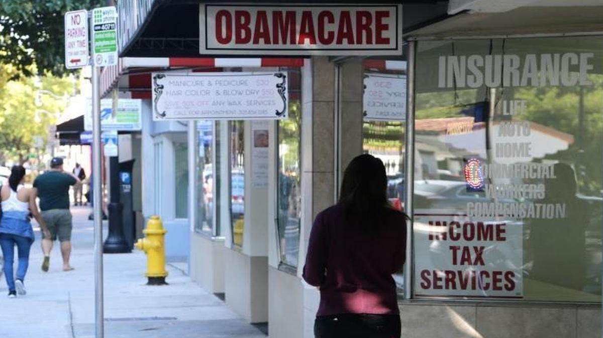 A woman walks past a sign advertising "Obamacare," Jan. 31, 2017, in Miami, Fl. President Donald Trump called the Affordable Care Act a “failed disaster” and told insurance company executives that the U.S. will replace it with “extraordinary” health care that will be “better than any other country anywhere in the world.”