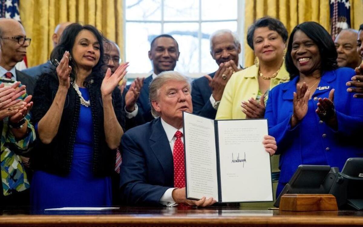 President Donald Trump holds up the Historically Black Colleges and Universities HBCU Executive Order after signing it, Feb. 28, 2017, in the Oval Office in the White House in Washington.