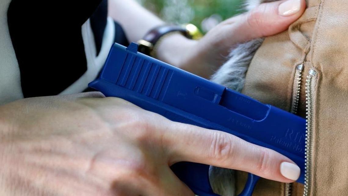 Marilyn Smolenski uses a mock gun to demonstrate how to pull a handgun out of the concealed carry clothing she designs at her home in Park Ridge, Ill. Interest in clothing that allow women to carry a firearm concealed is rising.