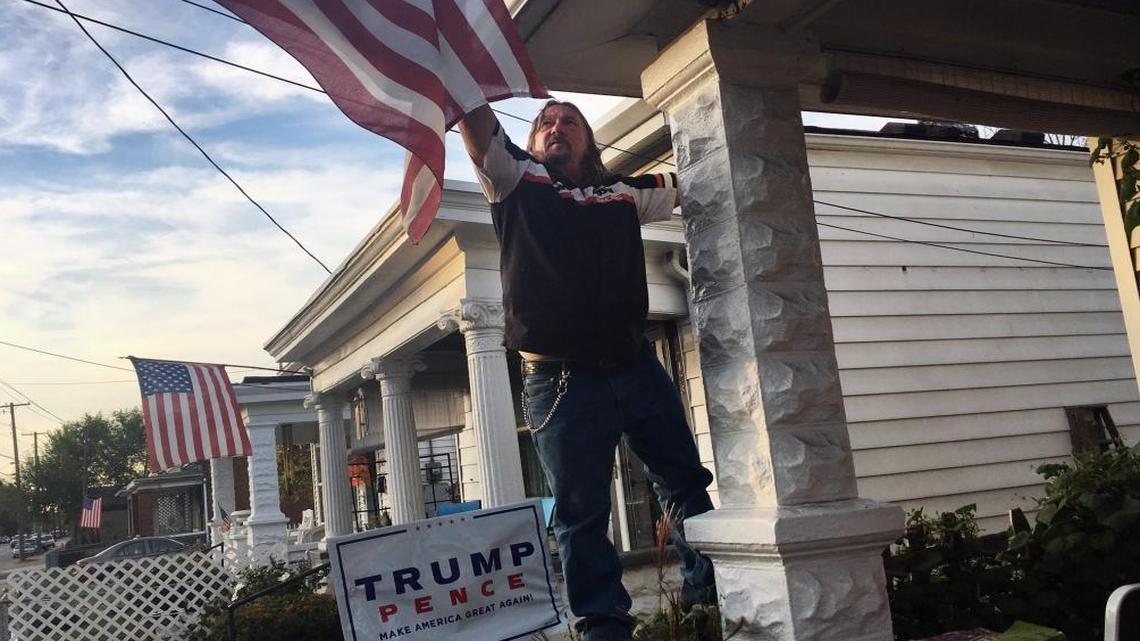 Terry Wright, a 59-year-old retired union painter, adjusts the U.S. flag on his porch in Portland, a white, working class neighborhood in Louisville, Ky., on Tuesday, Nov. 1, 2016. Wright, a registered Democrat backing Republican presidential candidate Donald Trump, says he has given up on his old party. Democrats backed immigration policies that have filled limited jobs with foreigners, and pushed for welfare programs that have knocked the ambition out of younger workers, he says. Clinton "will be the damnation of America," he says.