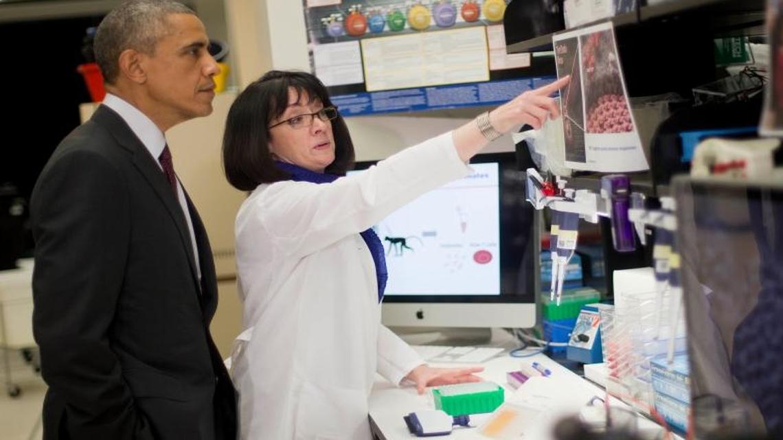 President Barack Obama listens to Dr. Nancy Sullivan during a tour of the Vaccine Research Center at the National Institutes of Health on Tuesday, Dec. 2, 2014, in Bethesda, Md.