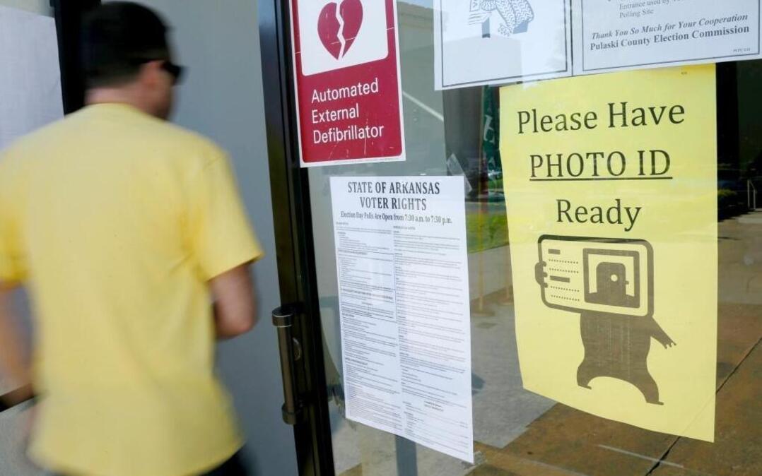 In this May 5, 2014, file photo, a voter walks past a "Please Have Photo ID Ready" sign as he enters an early-voting polling place in downtown Little Rock, Ark. Arkansas lawmakers approved a measure requiring voters to show photo identification before casting ballots, and Gov. Asa Hutchinson signed it March 24, 2017. A similar bill was struck down by a court more than two years ago.
