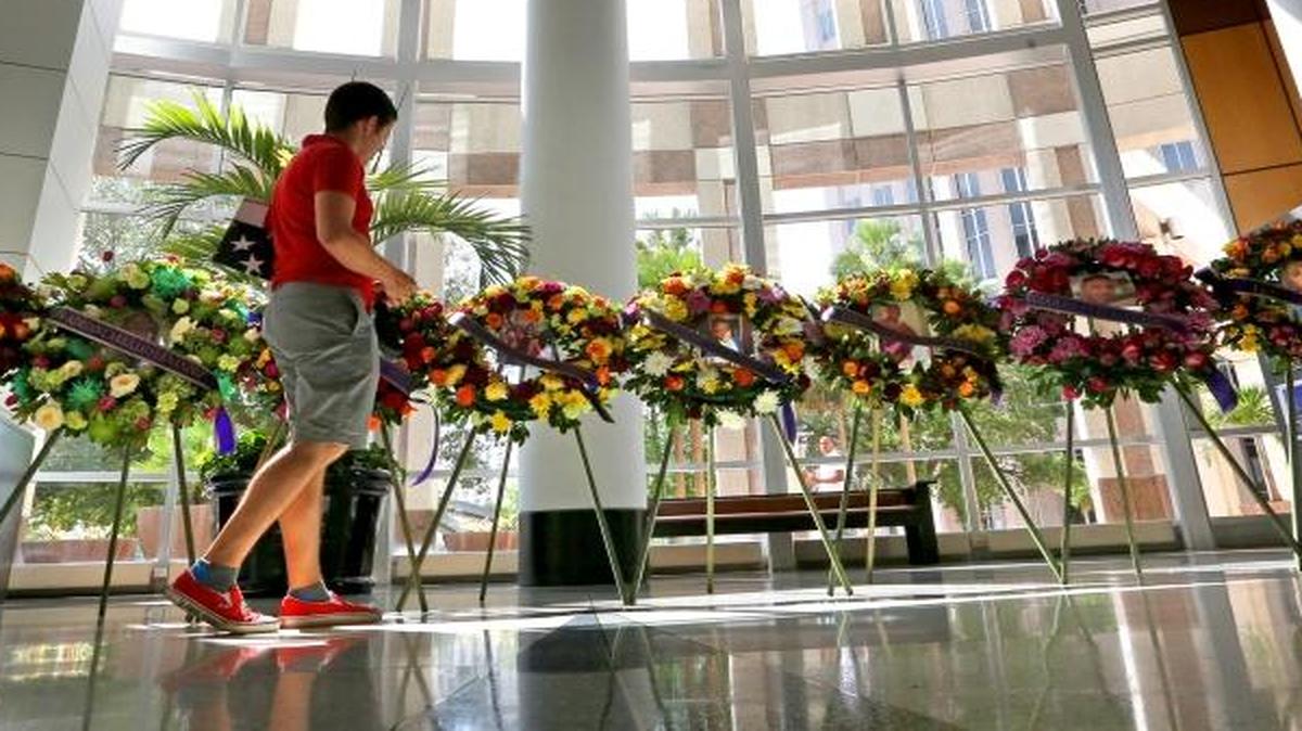 Visitors survey some of the 49 floral wreathes, provided by private donations, that adorn the rotunda of Orlando City Hall, Friday, June 17, 2016, to honor each of the victims of the Pulse massacre in Orlando.
