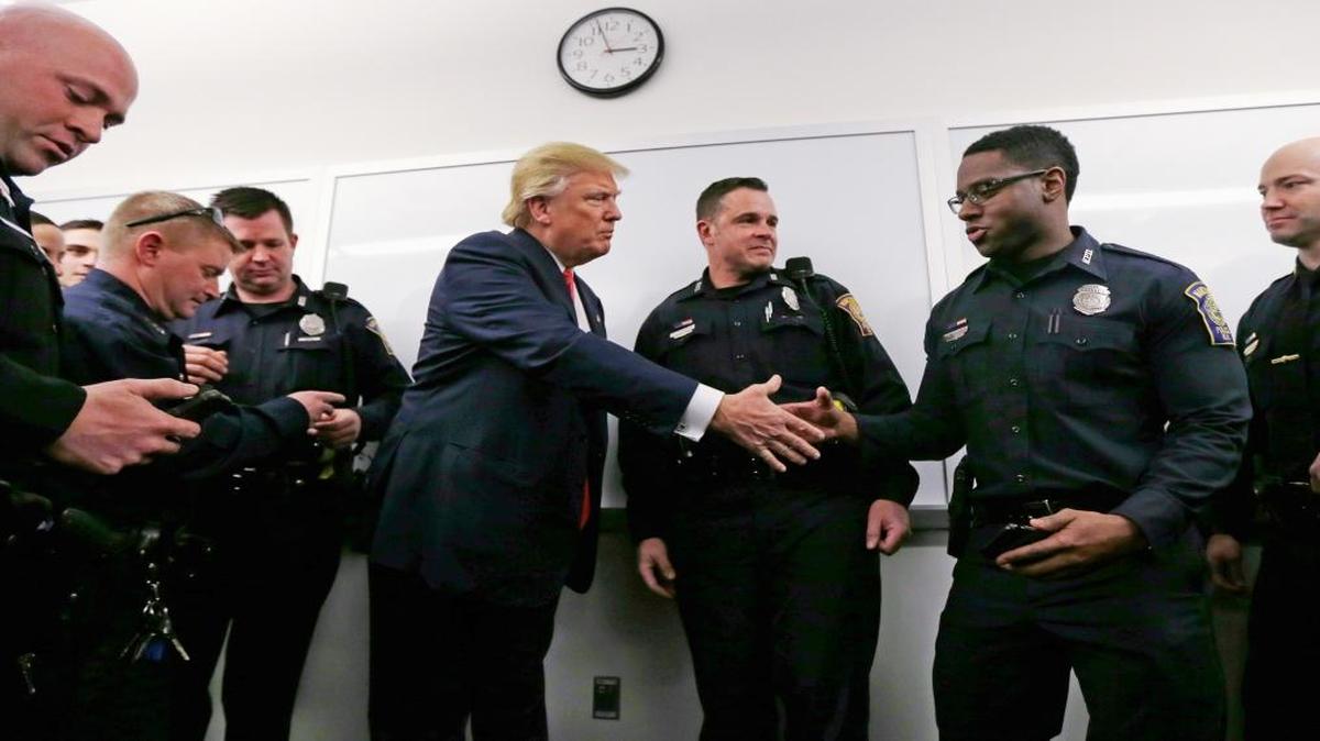 Republican presidential candidate Donald Trump shakes hands with a patrolman while other officers look at photographs of them posing with Trump on Thursday, Feb. 4, 2016, during a campaign stop at police headquarters in Manchester, N.H.