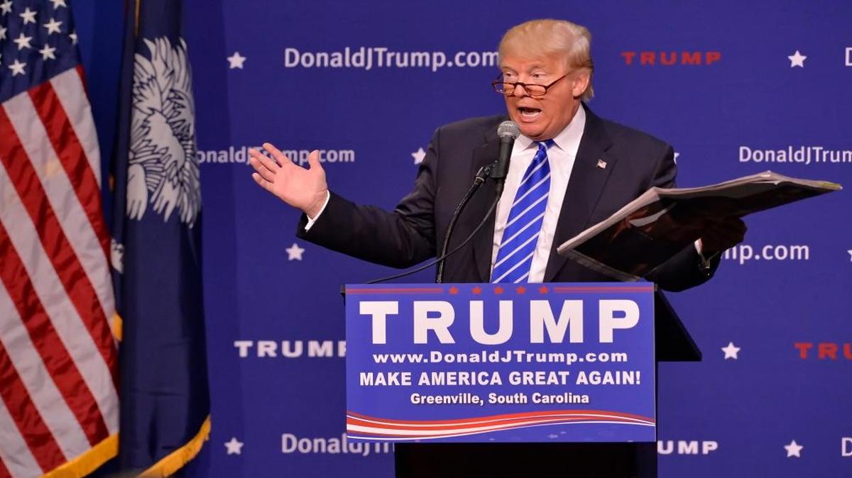 
Republican presidential candidate Donald Trump holds a copy of The New York Times, in which it said he wore a toupee, during a rally at the TD Convention Center, Thursday, Aug. 27, 2015, in Greenville, S.C. 
