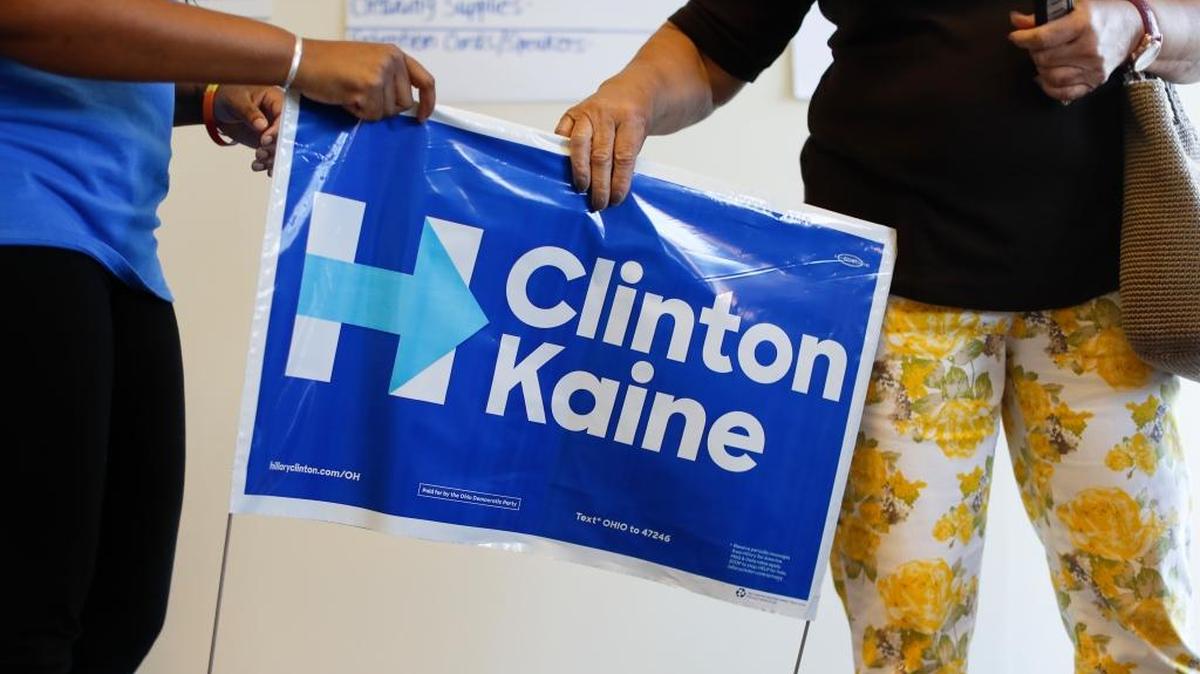 A volunteer hands a lawn sign to a supporter at a newly-opened organizing office for Democratic presidential candidate Hillary Clinton in the Roselawn neighborhood of Cincinnati.