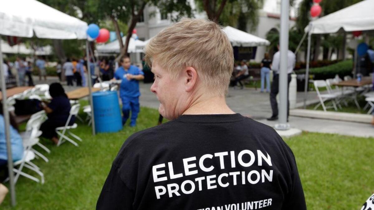 Lisa Hubbard, a volunteer with the non-partisan Election Protection Coalition, attends an early voting celebration outside of Jackson Memorial Hospital, on the first day of early voting in Miami-Dade County for the general election, Monday, Oct. 24, 2016, in Miami. The event was organized by local unions and immigrant groups to encourage people to vote during the two week early voting period. (AP Photo/Lynne Sladky)