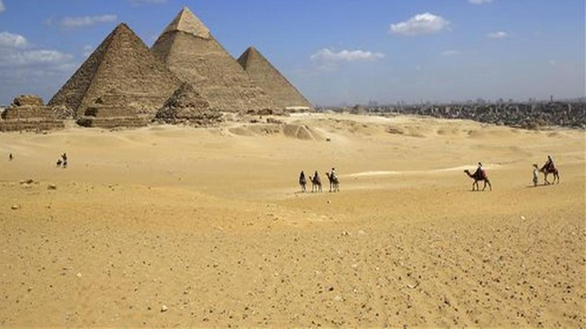 In this April 9, 2015, file photo, tourists ride camels at the historical site of the Giza Pyramids in Giza, near Cairo, Egypt. Republican presidential candidate Ben Carson says its still his belief the great pyramids Egypt were built by the Biblical figure Joseph to store grain, and not as tombs for pharaohs.
