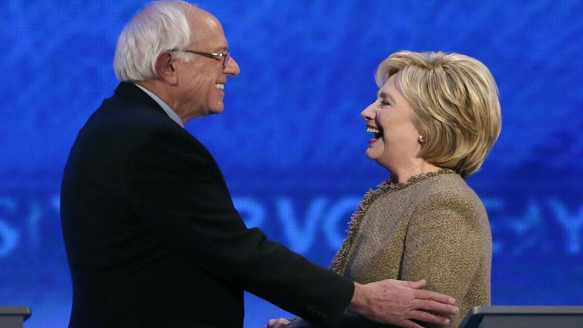 Bernie Sanders, left, speaks with Hillary Clinton during the Democratic presidential primary debate at Saint Anselm College in Manchester, N.H. on Saturday, Dec. 19, 2015.