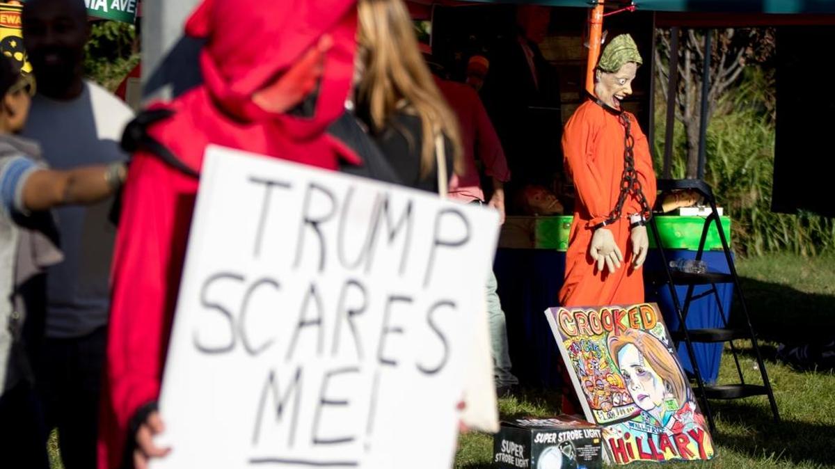 A supporter for Democratic presidential candidate Hillary Clinton wears a halloween costume outside and holds a sign that reads "Trump scares me!" before the second presidential debate at Washington University, Sunday, Oct. 9, 2016, in St. Louis.