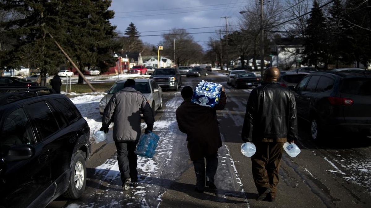 Flint residents Marcus Shelton, from left, Roland Young, and Darius Martin walk on an ice-covered street as they retrieve free water on Sunday, Jan. 17, 2016, at Heavenly Host Full Gospel Baptist Church in Flint, Mich. Flint's water became contaminated after Flint switched from the Detroit water system to the Flint River as a cost-cutting move.