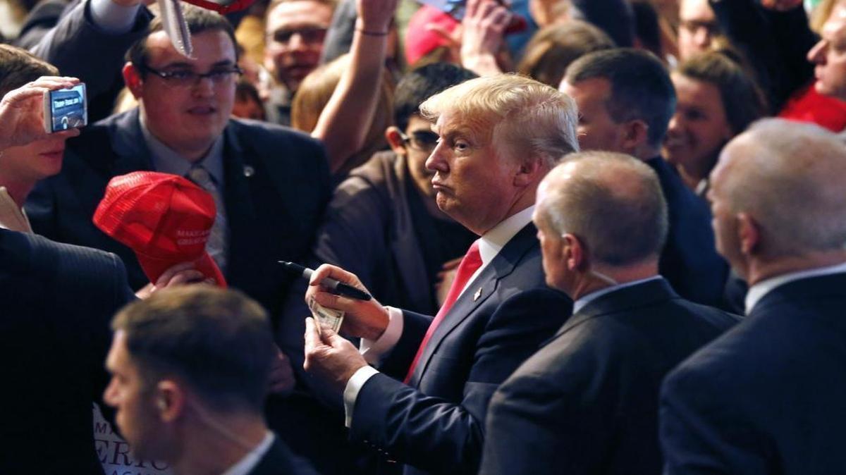 Republican presidential candidate Donald Trump looks down the row of supporters before signing an autograph on a dollar bill during a rally at the Milwaukee Theatre on Monday, April 4, 2016, in Milwaukee.