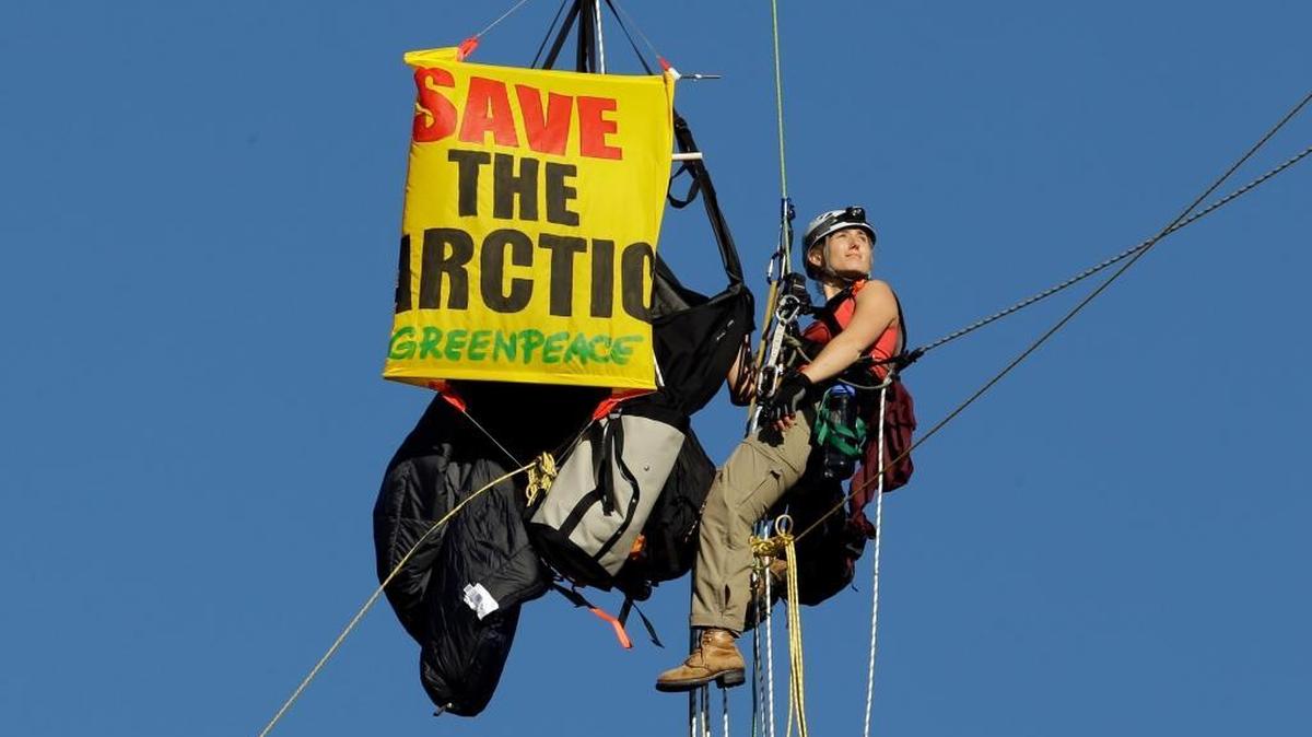 
An activist looks towards the rising sun as she hangs from the St. Johns bridge as part of a protest to block the Royal Dutch Shell PLC icebreaker Fennica from leaving for Alaska in Portland, Ore., Thursday, July 30, 2015. The icebreaker, which is a vital part of Shell's exploration and spill-response plan off Alaska's northwest coast, stopped short of the hanging blockade, turned around and sailed back to a dock at the Port of Portland. On Monday, Aug. 17, 2015, the Interior Department said it would let Shell drill deep enough off Alaska’s northwest coast to find oil. (AP Photo/Don Ryan)
