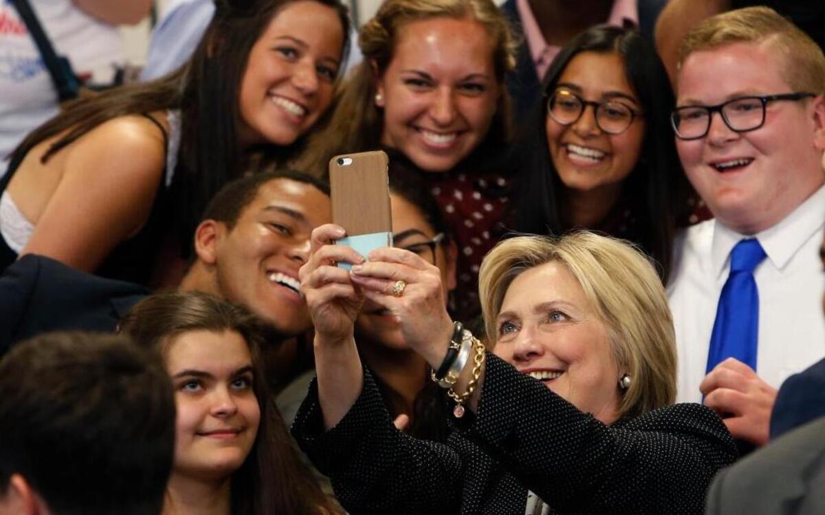 In this June 21, 2016, file photo, Democratic presidential candidate Hillary Clinton takes a photo with supporters after speaking at Fort Hayes Vocational School in Columbus, Ohio. A new poll finds that young voters are starting to come through for Clinton, particularly whites ages 18 to 30.