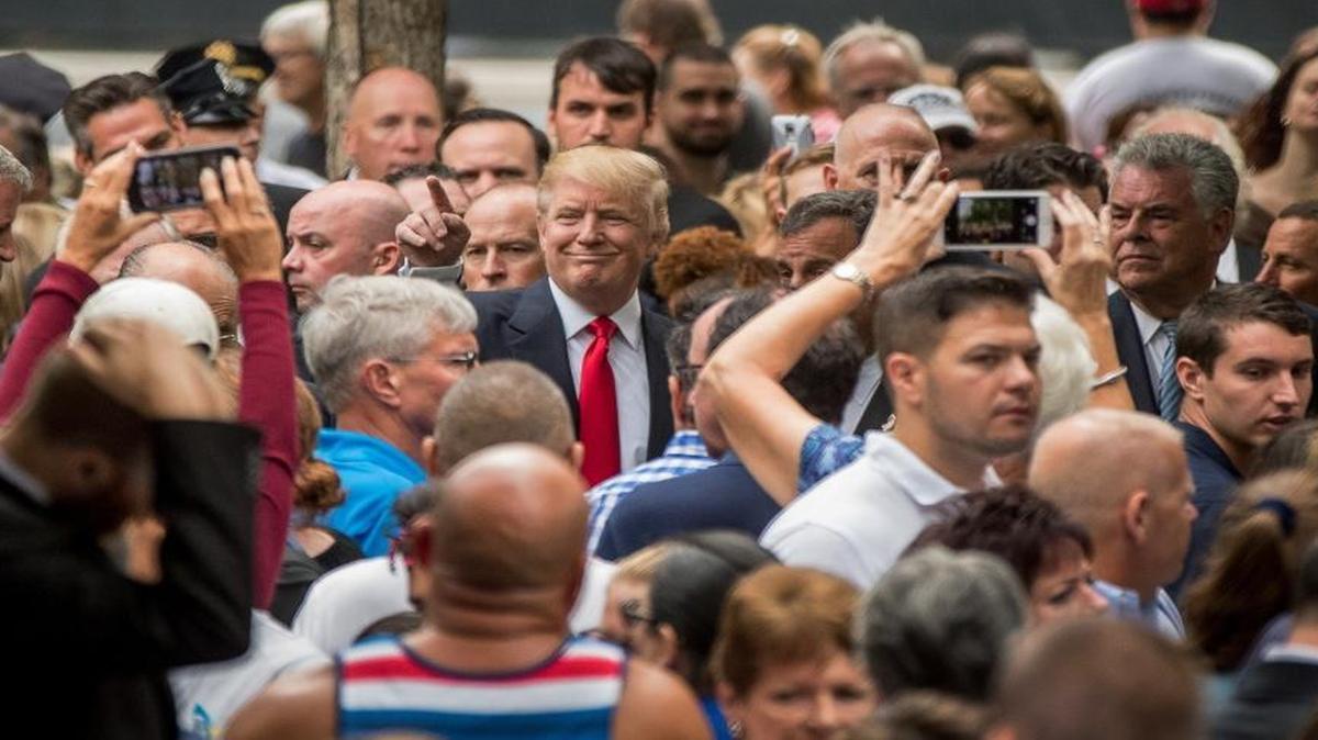Republican presidential candidate Donald Trump, center, greets members of the audience as he attends a ceremony at the National September 11 Memorial, in New York, on Sept. 11, 2016.