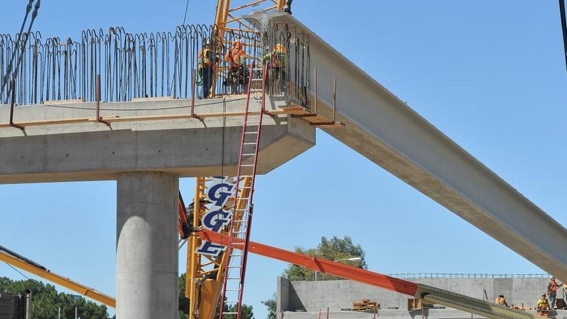 Workers fit a girder onto a support structure during construction by contractors of the California High-Speed Rail Authority of a new bridge in downtown Fresno, Calif., on Thursday, June 16, 2016.