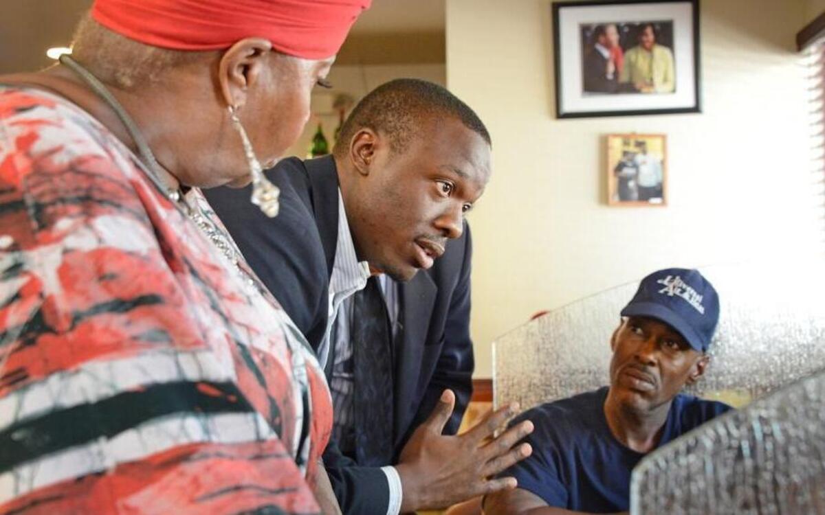 Akua Scott and Aaron McKinney, left and center, community organizers in South Florida, speak with customers at Jackson's Soul Food restaurant, a popular gathering place for many living in District 24, about voter turnout, in Overtown, Fla., on Oct. 9, 2014.