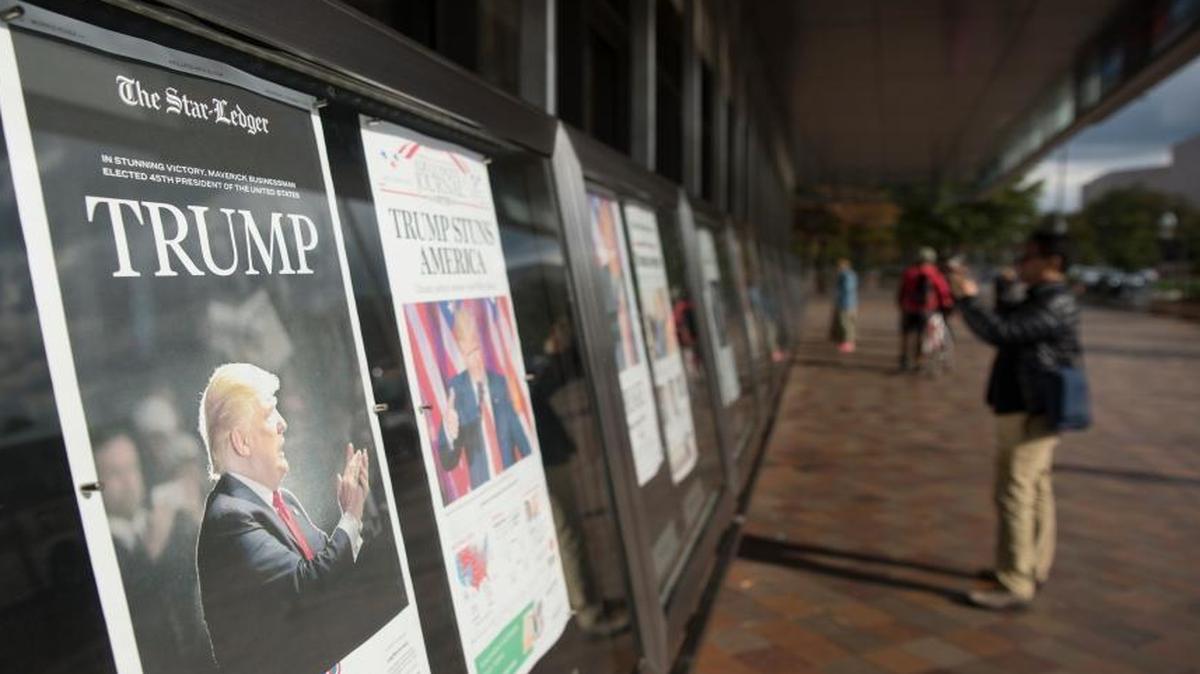 Passers by look at the multitude of different newspapers lined up outside of the Newseum in Washington, D.C. declaring Donald Trump's victory. Wed., Nov. 9, 2016.