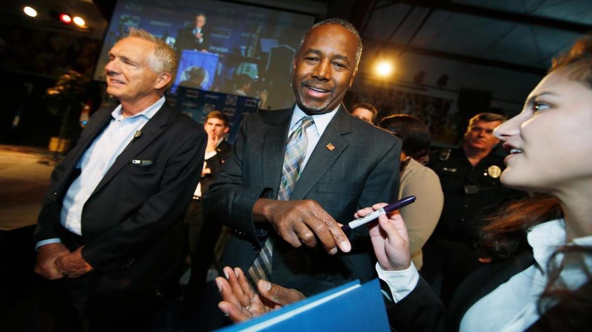 Republican presidential candidate Ben Carson signs a book for a woman during a campaign stop in Lakewood, Colorado.