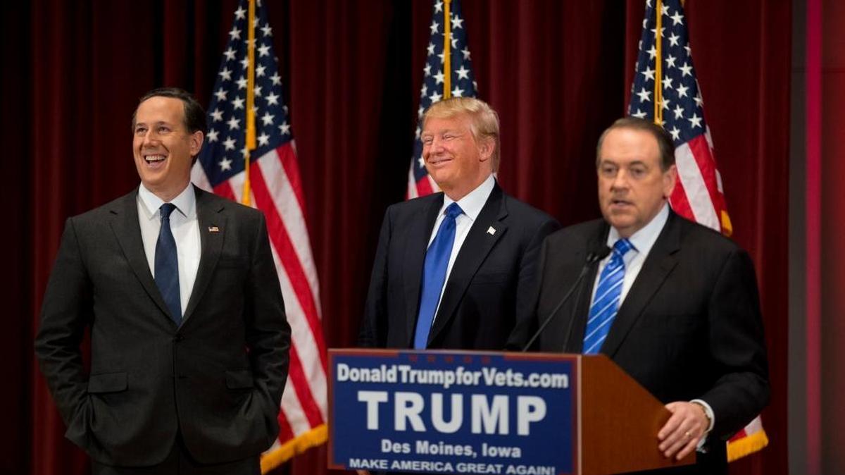 Republican presidential candidates Rick Santorum, left, and Donald Trump, center, laugh as they listen to Mike Huckabee during a campaign event on the campus of Drake University Thursday, Jan. 28, 2016, in Des Moines, Iowa.
