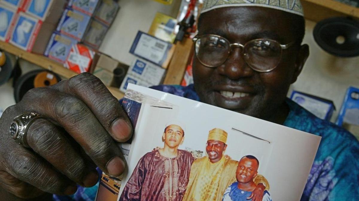This Tuesday, Sept. 14, 2004 file photo shows Malik Obama, the older brother of US President Barack Obama, who holds an undated picture of Barack, left, and himself, center, and an unidentified friend in his shop in Siaya, eastern Kenya. A Kenyan half-brother of President Barack Obama says he will vote for Republican presidential nominee Donald Trump and not the candidate his brother has endorsed, Hillary Clinton. Malik Obama told The Associated Press on Tuesday that he thinks Trump has a lot of energy and is very straightforward.