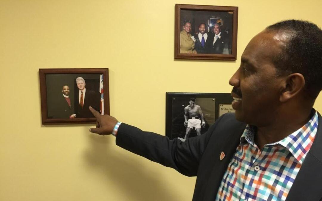 Bishop Wayne T. Jackson of Great Faith Ministries International will host Republican presidential nominee Donald Trump at his predominantly black church on Saturday, Sept. 3, 2016, in Detroit as Trump looks to court African-American voters. Jackson points to a picture on his office wall of himself with former President Bill Clinton on Friday, Sept. 2, 2016.